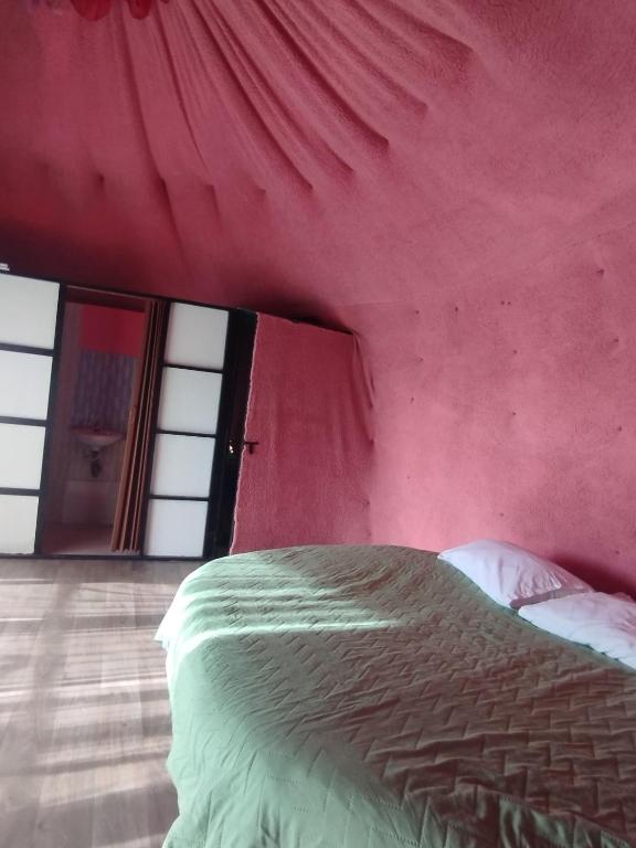 a bed in a room with a red wall at Marju Glamping in Manizales