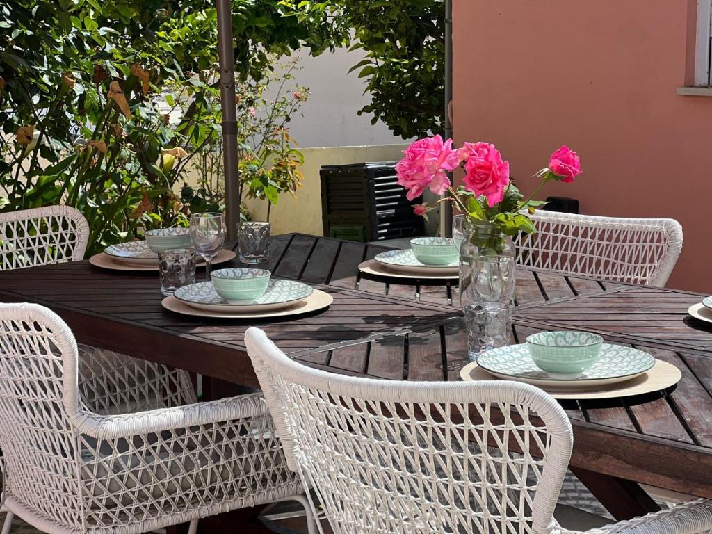 a wooden table with chairs and pink flowers on it at Quinta das Rosas - Beach 500m away in Figueira da Foz