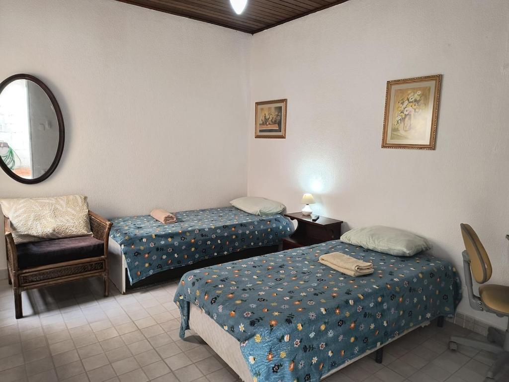 een kamer met 2 bedden, een stoel en een spiegel bij SuÍte 4 Completa com Wi-Fi e Netflix in Jundiaí