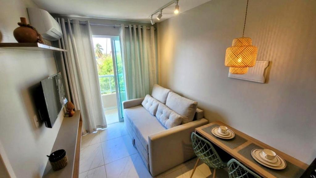 een woonkamer met een bank en een tv bij Cupe Living - VSH in Porto De Galinhas