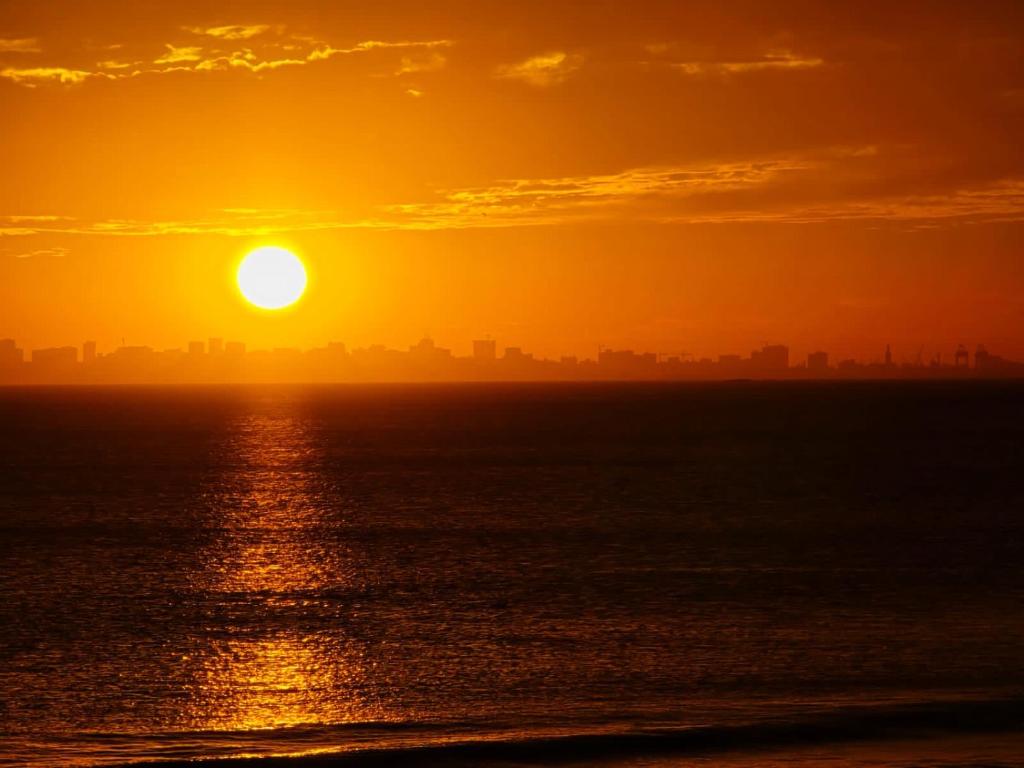 un tramonto sull'oceano con una città sullo sfondo di Grand Mbao a Mbaw