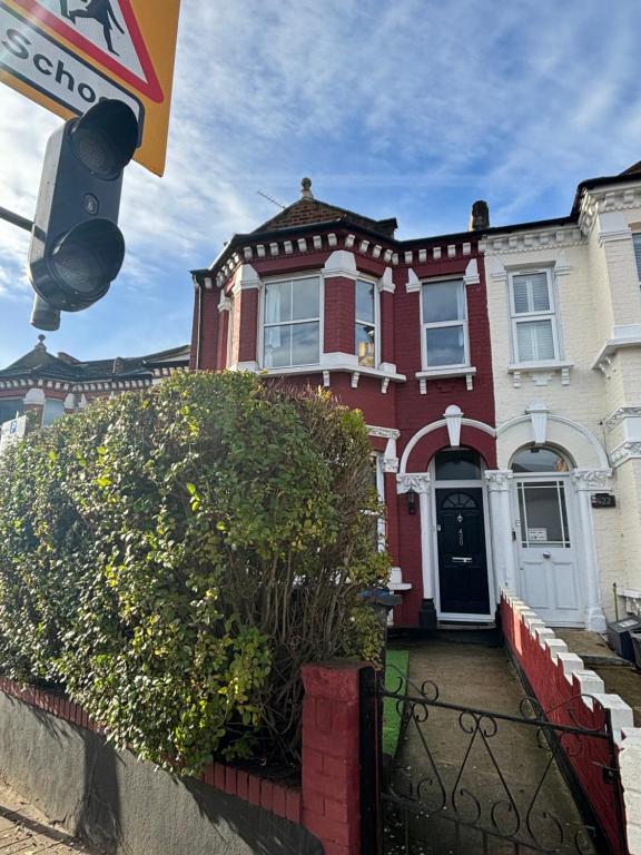 ein rotes Haus mit einem Straßenschild davor in der Unterkunft Spacious double room close to Wimbledon Park station, 20 min to central in London