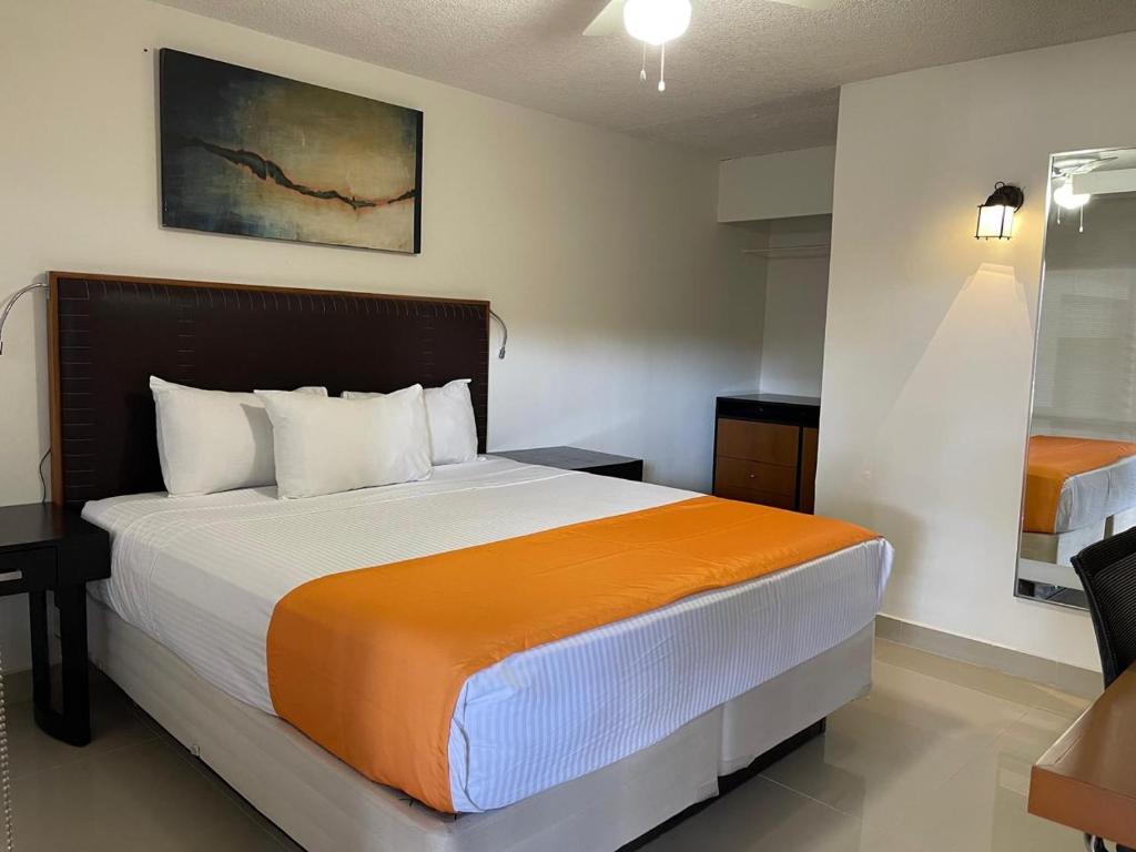 a bedroom with a large bed with an orange blanket at Hotel Presidente Tijuana in Tijuana