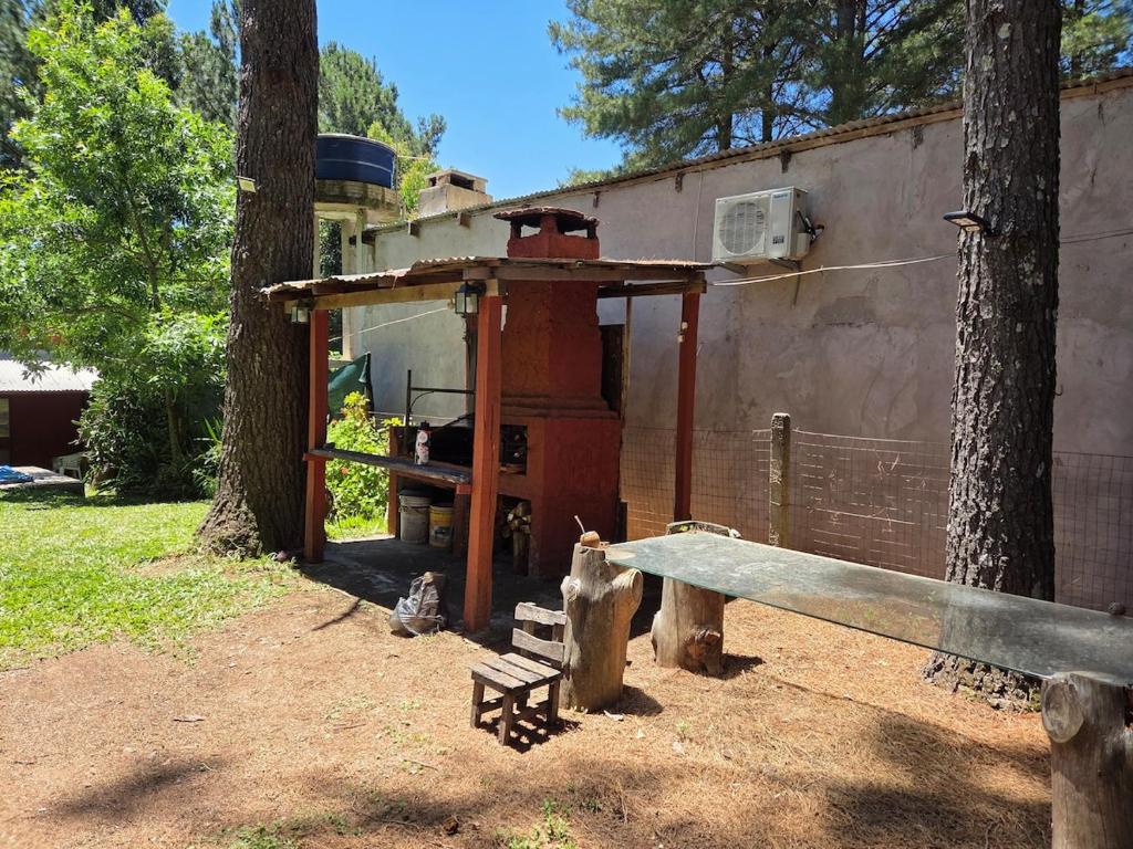 a grill with a bench next to a tree at Nido Rústico in Rivera