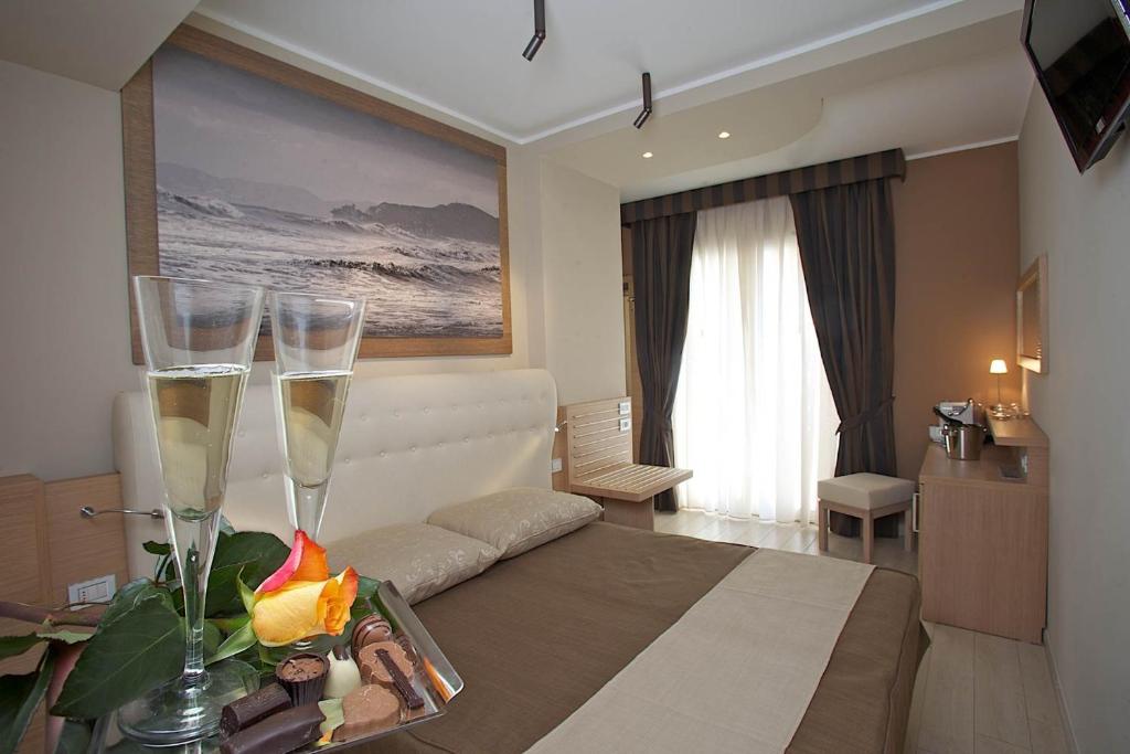 a hotel room with two champagne glasses on a bed at Hotel C'era Una Volta in Castiglione della Pescaia