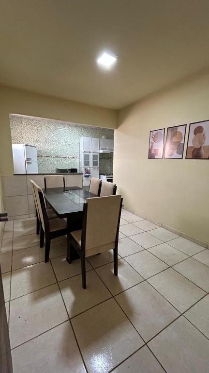 a dining room with a table and chairs and a kitchen at Casa Aconchegante Uberlândia in Uberlândia