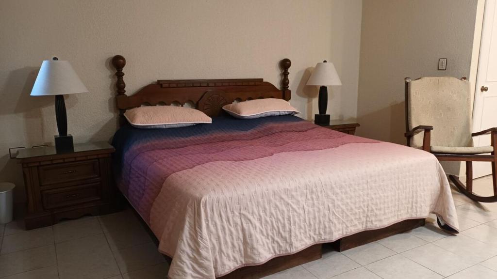 维多利亚城Residencia completa 2 recamaras para 4 con cochera的一间卧室配有一张大床、两盏灯和一把椅子