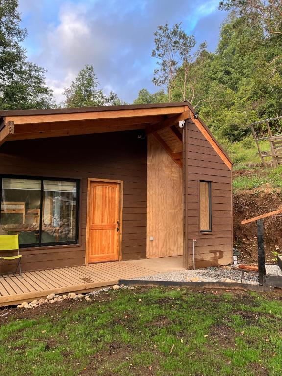 eine kleine Hütte mit Veranda und Holztür in der Unterkunft Cabaña Los Arrayanes 2 in Coihueco