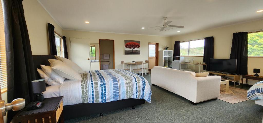 une chambre avec un lit, un canapé et une chaise dans l'établissement Avocado Orchard Retreat!, à Katikati