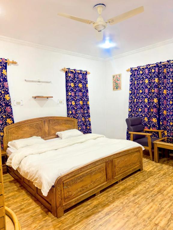 a bedroom with a wooden bed and blue curtains at Greenoriva Aero Srinagar in Srinagar