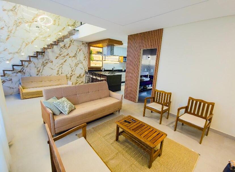 een woonkamer met een bank en twee stoelen bij Refúgio da felicidade in Imbassai
