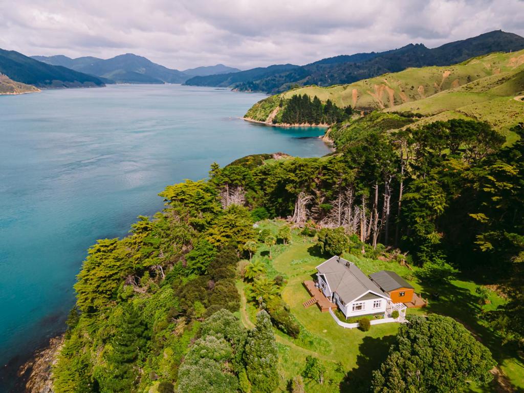 a house on a hill next to a body of water at Arapawa Homestead in Picton