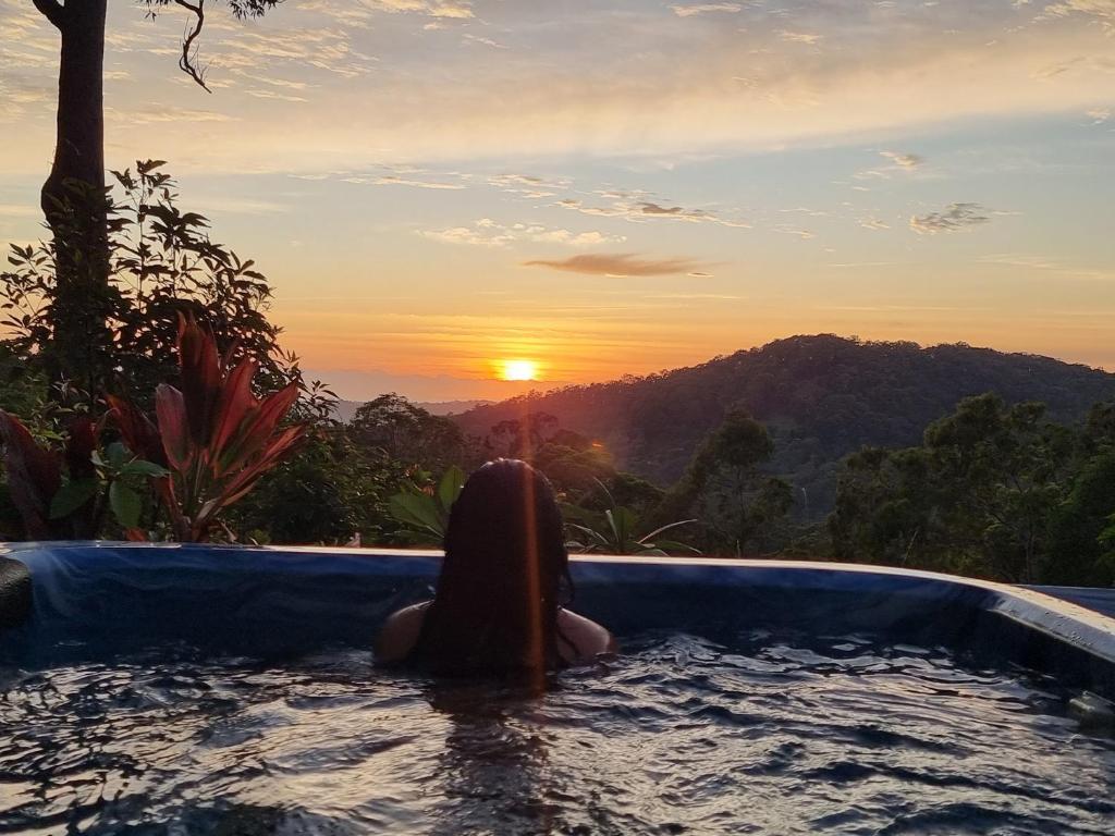Eine Frau, die im Pool sitzt und den Sonnenuntergang beobachtet. in der Unterkunft Gold Coast Hinterland Experience No ppl 8 in Tallebudgera