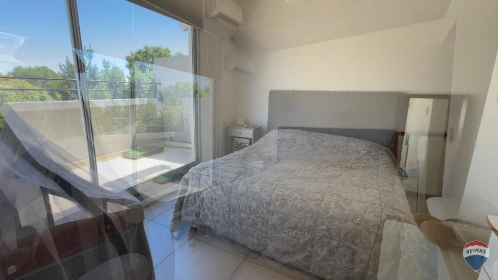 een slaapkamer met een bed en een groot raam bij Homero duplex in Villa Gesell