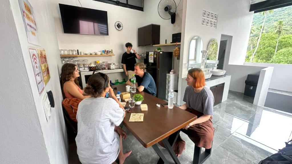 un gruppo di persone seduti intorno a un tavolo in una cucina di Cosy Hostel a Ko Tao