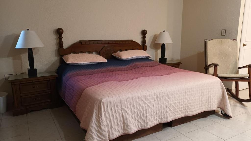 维多利亚城Casa Cd Victoria 1V的一间卧室配有一张带两盏灯和一把椅子的床。