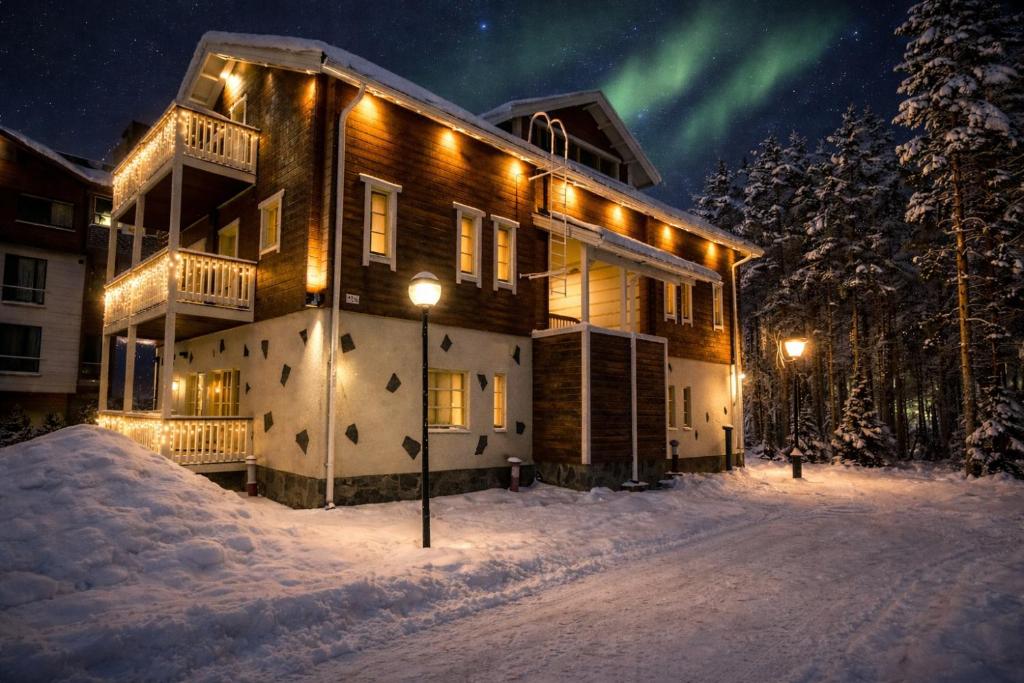 een huis in de sneeuw 's nachts met het noorderlicht bij Levillenet Levi centre chalets in Levi