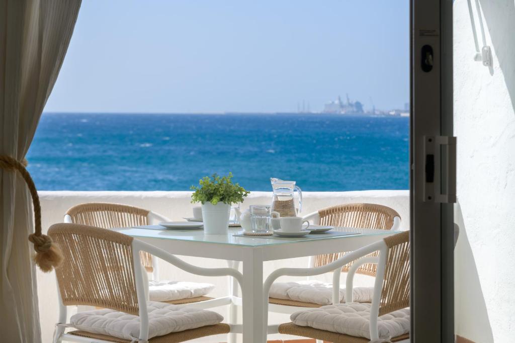 een witte tafel en stoelen met uitzicht op de oceaan bij La Vida Oceana in Costa Teguise