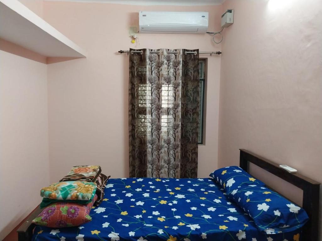 een slaapkamer met een bed met blauwe lakens en een raam bij Allô Gite in Pondicherry