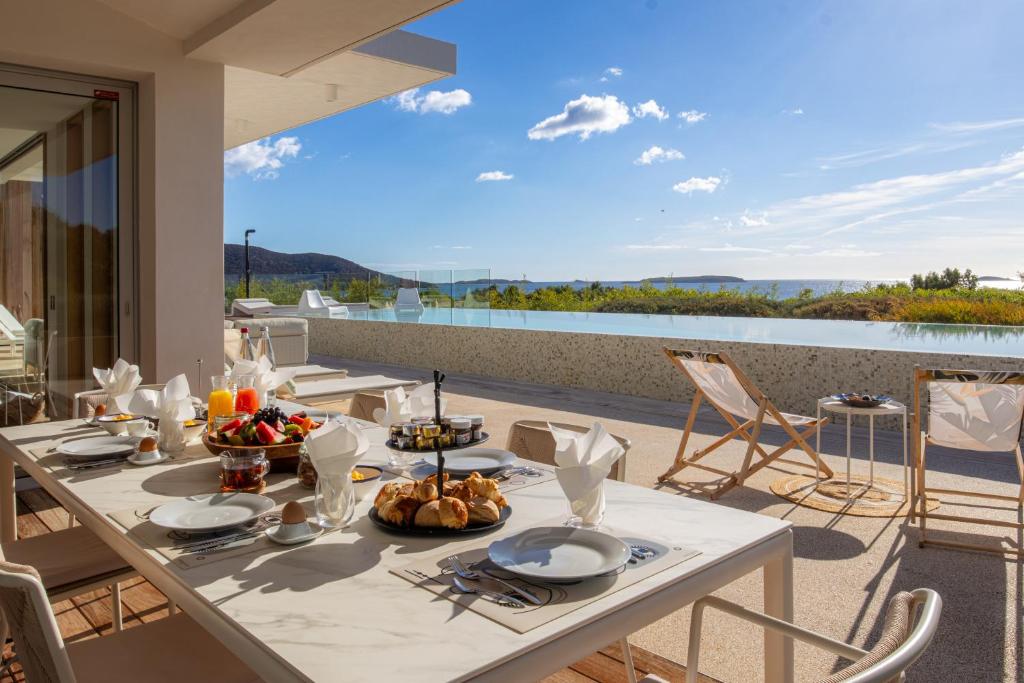 une table sur un balcon avec vue sur l'eau dans l'établissement Villa AzaiTu Suites, à Porto-Vecchio