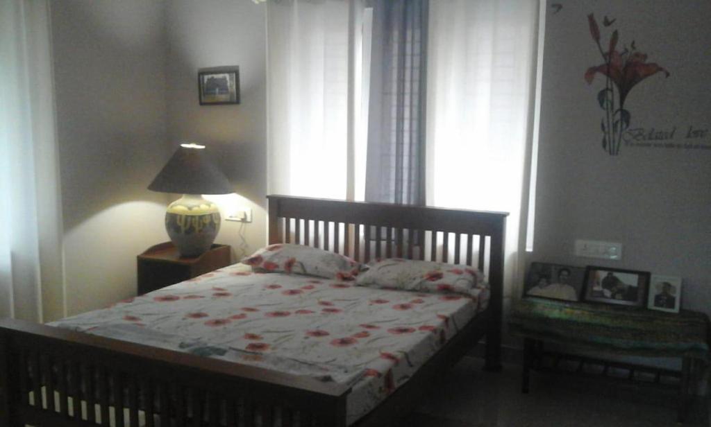 a bedroom with a bed and a lamp and a window at Parthipuram in Thottada