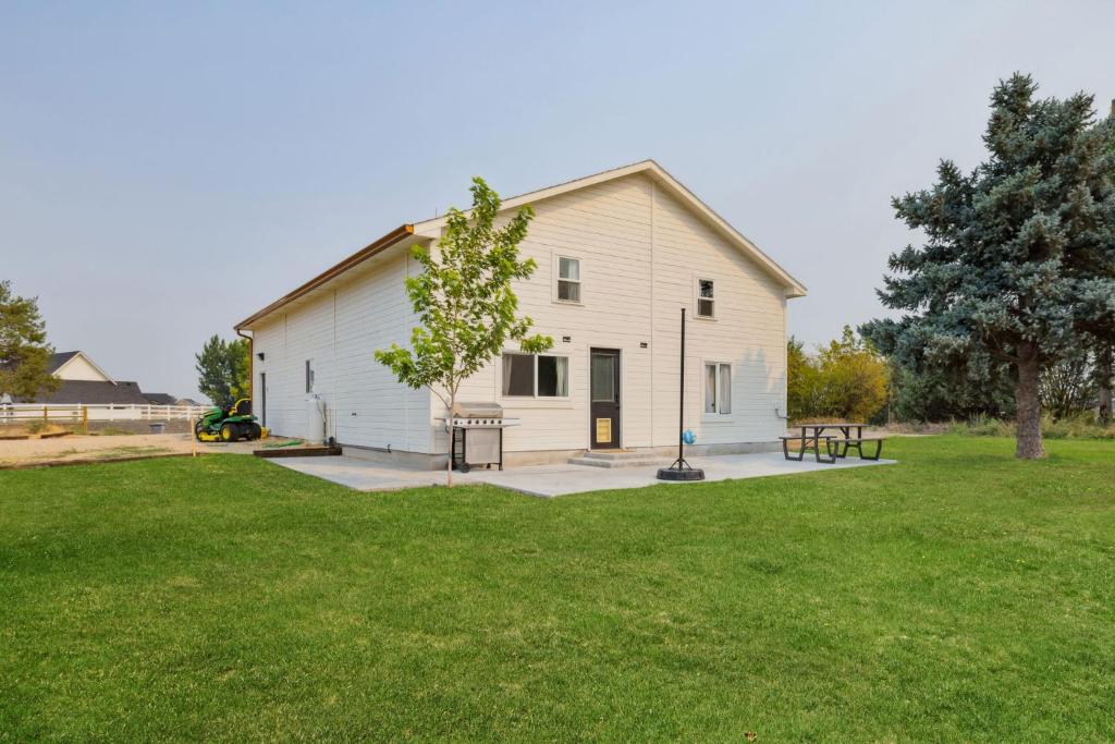 een wit gebouw met een picknicktafel in een tuin bij Quail Run Loft in Caldwell