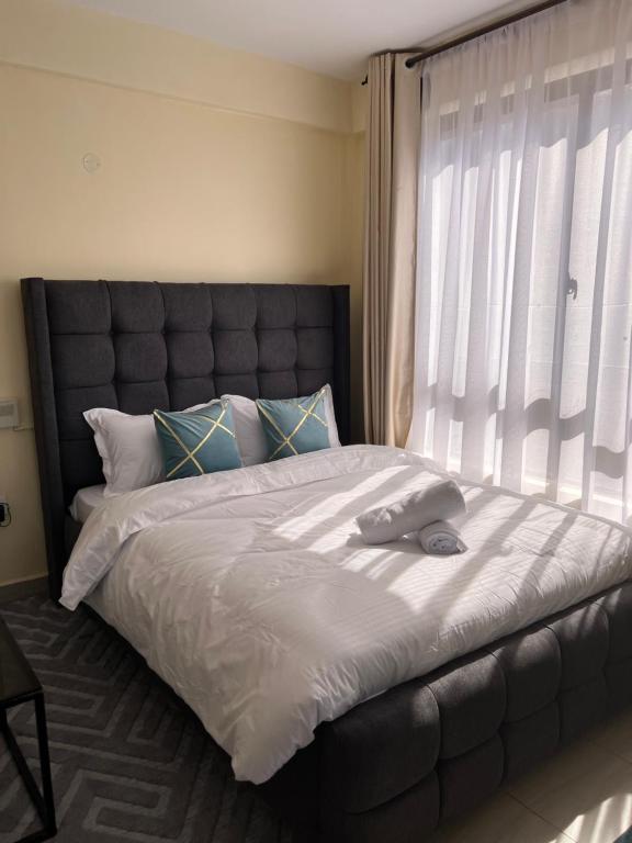 a bedroom with a large bed with a large window at Lora's Haven Homes - Kikuyu Studio in Rungiri