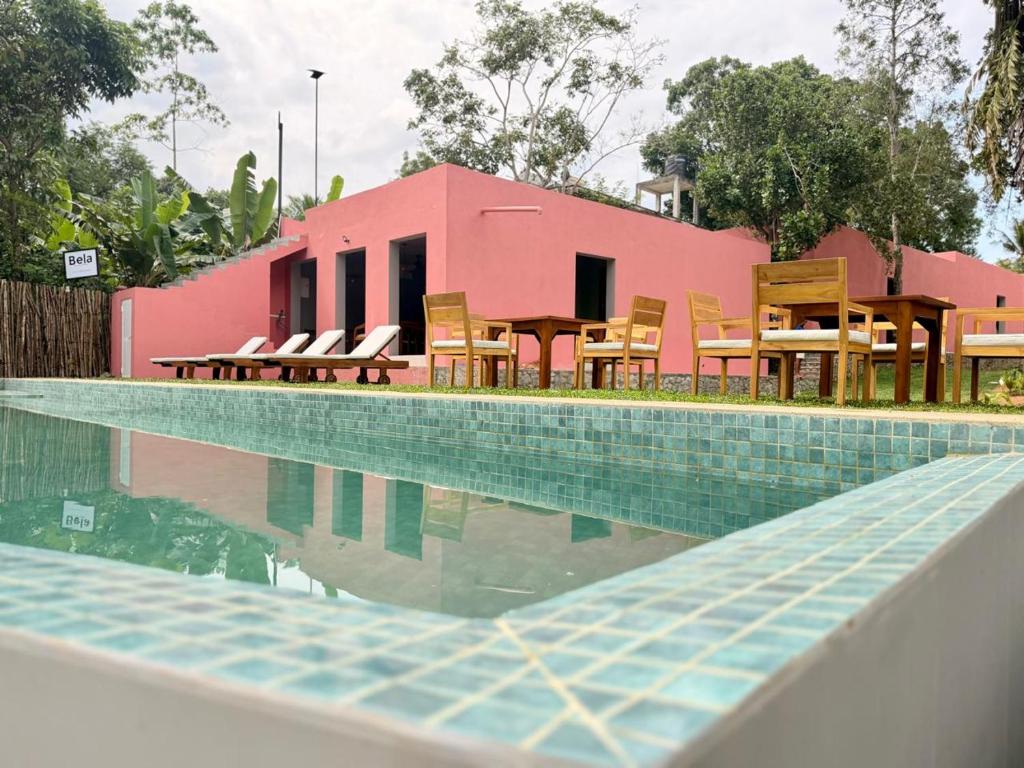 une piscine avec des chaises et un bâtiment rose dans l'établissement Bela Ahangama, à Ahangama