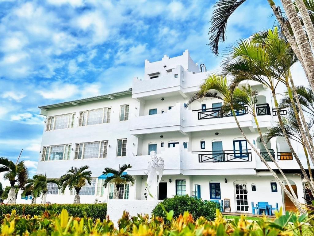 een wit gebouw met palmbomen ervoor bij Canaan B&B Kenting in Eluan