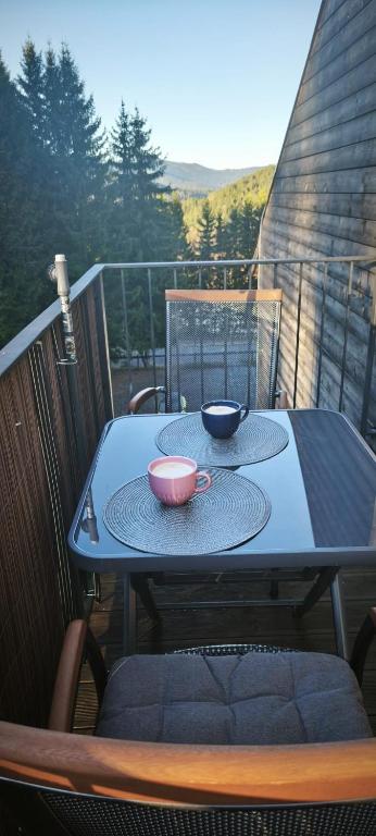 a table on a balcony with two bowls on it at Apartmán Nest Brčálník in Železná Ruda