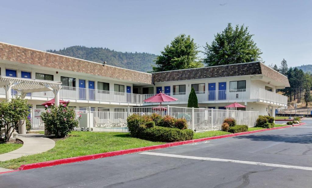 ein Gebäude mit rosa Sonnenschirmen vor einer Straße in der Unterkunft Motel 6-Grants Pass, OR in Grants Pass