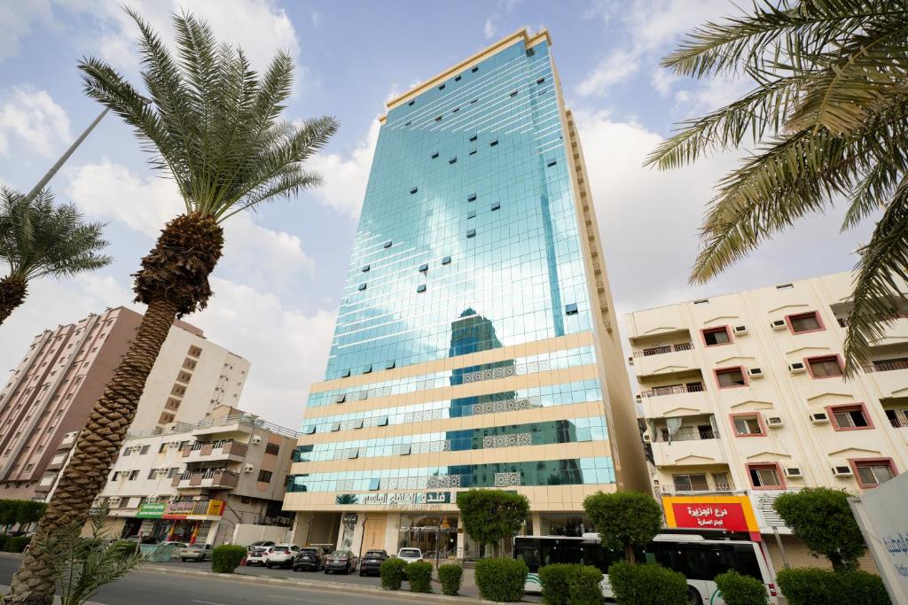 a tall building with a palm tree in front of it at Al Khulfaa Al Masy - فندق الخلفاء الماسي in Makkah