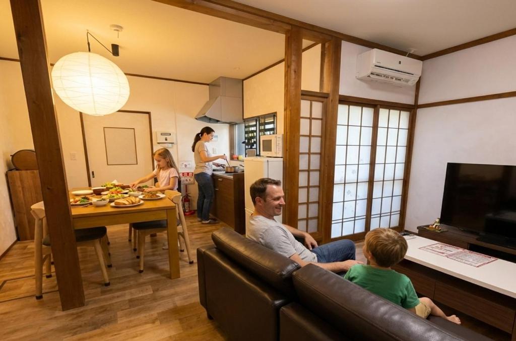 Ein Mann und ein Kind sitzen auf einer Couch im Wohnzimmer in der Unterkunft Private House HidaTakayama in Takayama