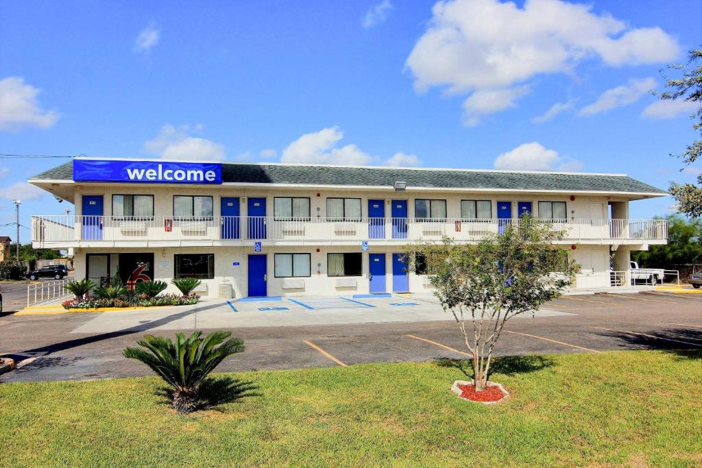a building with a welcome sign in a parking lot at Motel 6-Kingsville, TX in Kingsville