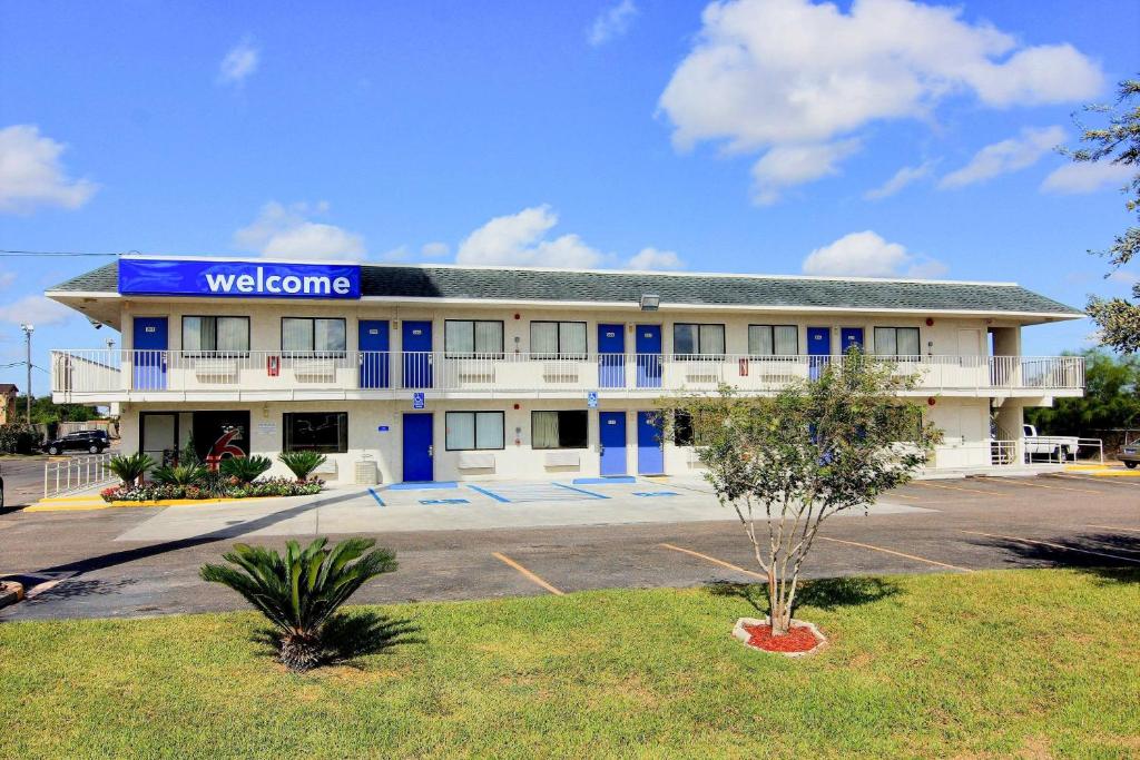 un edificio con un cartel de bienvenida en un aparcamiento en Motel 6-Kingsville, TX, en Kingsville