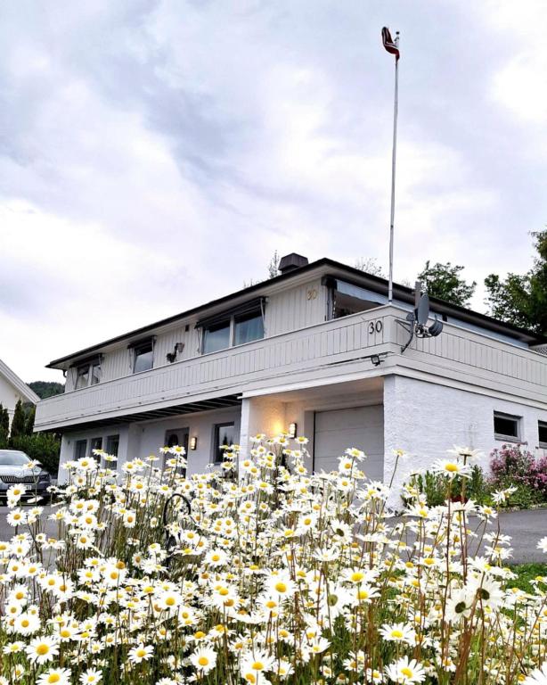 a building with a field of flowers in front of it at Gjesterom til leie i et privat hus 250 moh in Brumunddalen