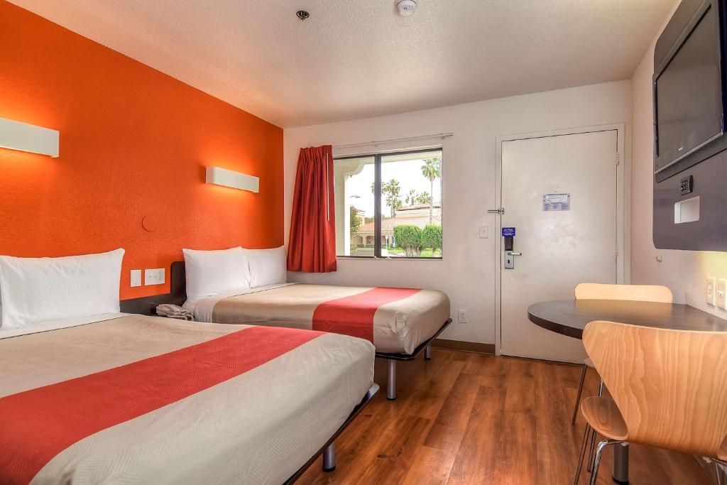 カールスバッドにあるMotel 6-Carlsbad, CA Beachのベッド2台とテーブルがあるホテルの部屋