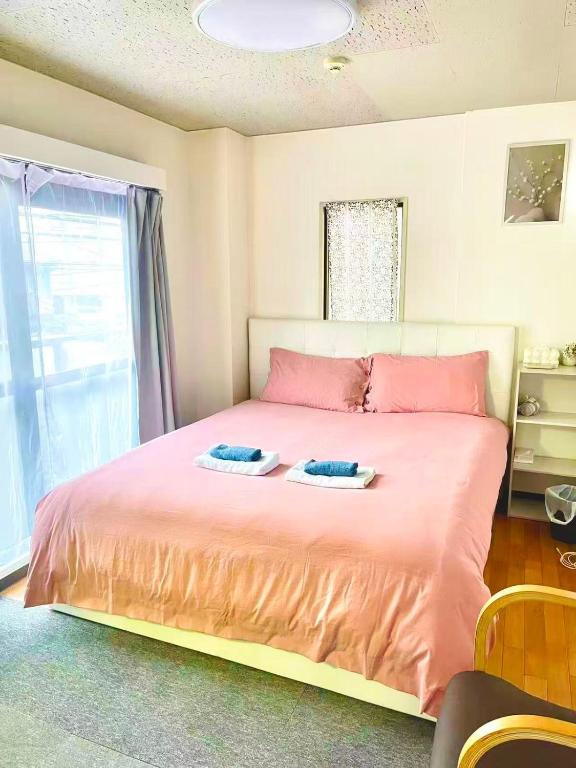 a bedroom with a large bed with pink sheets at Peace 平和屋 in Osaka