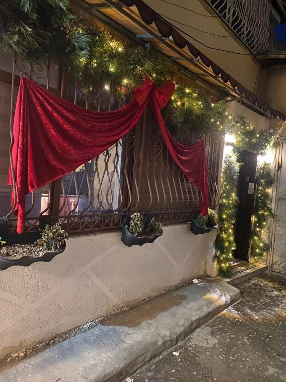 a window with a red curtain and christmas lights at Romeo apt with private garden in Korçë