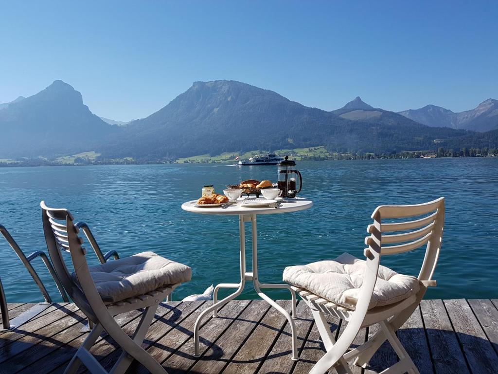 a table and chairs on a dock with a table and water at Haus Seegarten in St. Wolfgang