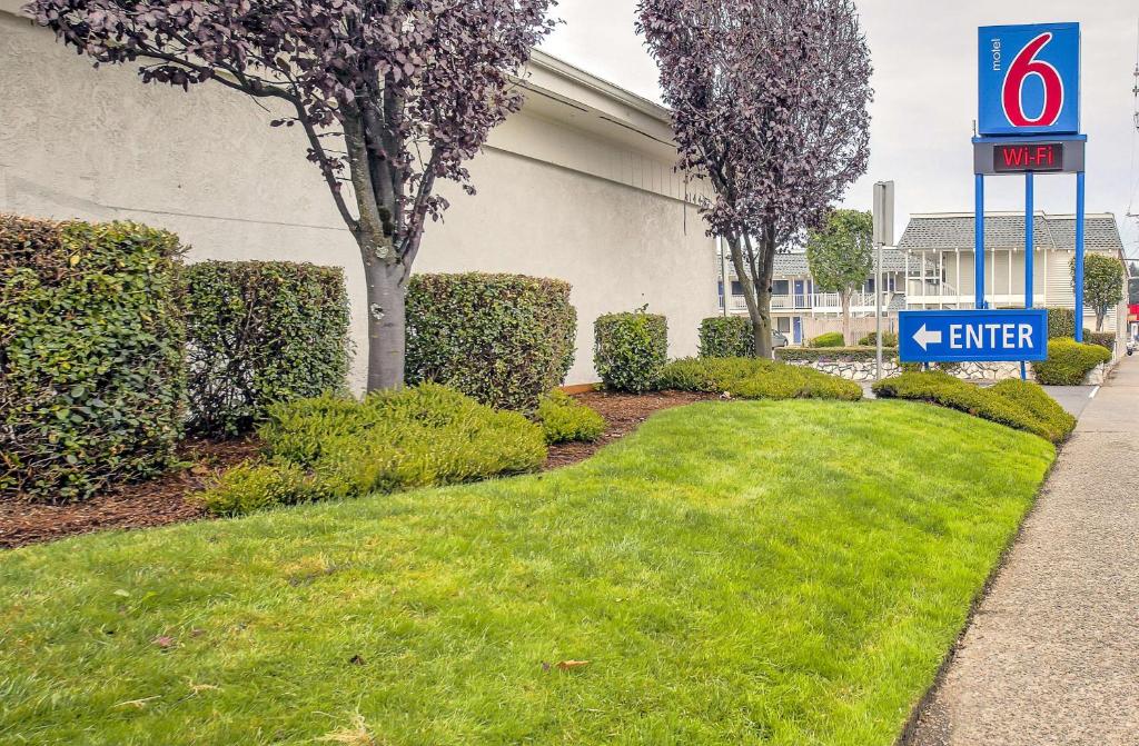 a sign in front of a building with a yard at Motel 6-Coos Bay, OR in Coos Bay
