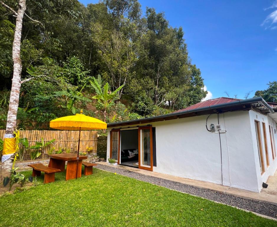 ein Haus mit einem Picknicktisch und einem gelben Regenschirm in der Unterkunft Little Munduk, full private villa in Munduk