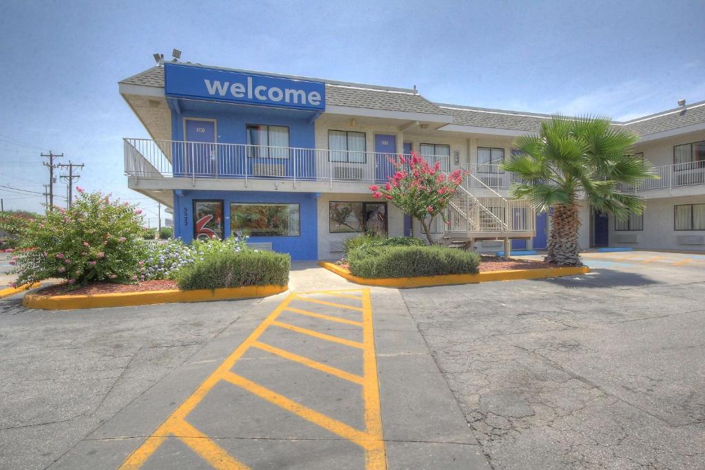 Motel 6-San Antonio, TX - Fort Sam Houston في سان انطونيو: مبنى عليه علامة ترحيب في موقف السيارات