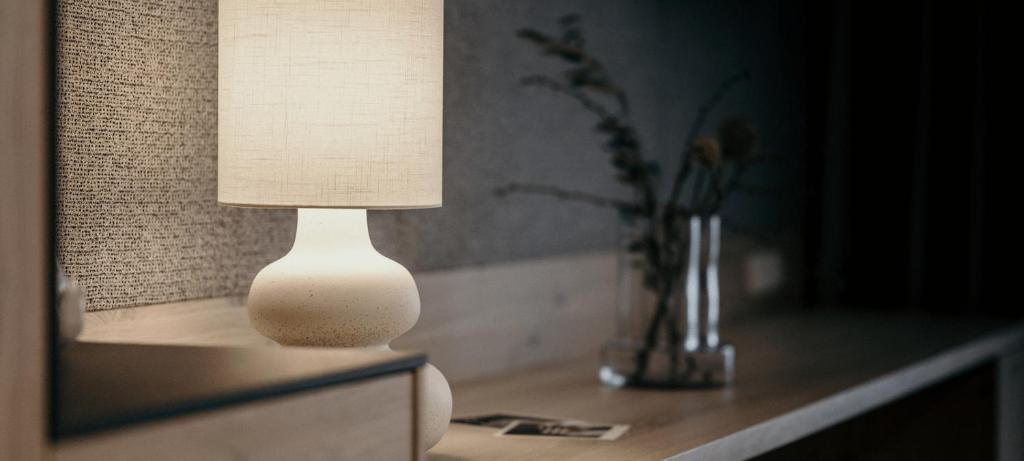 Eine weiße Lampe steht auf einem Tisch mit einer Vase. in der Unterkunft Sonnhof Alpendorf - an adults only place in St. Johann im Pongau