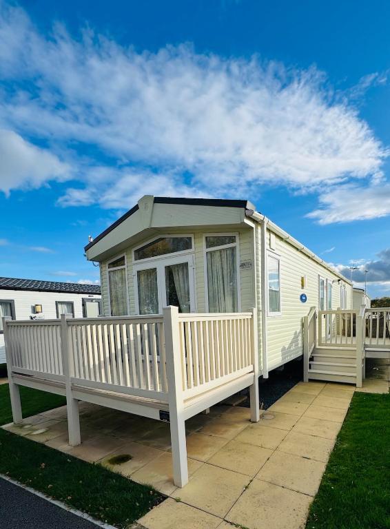 a white mobile home with a porch and benches at Princess's Palace, Holiday Lodge, Malvern View Leisure Park in Stanford Bishop