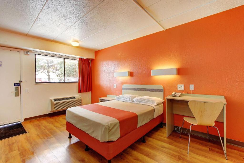 Habitación naranja con cama y escritorio en Motel 6-York, PA, en York