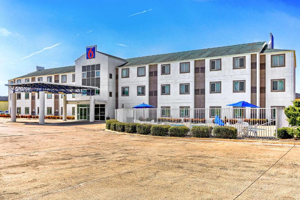 ein großes weißes Gebäude mit blauen Sonnenschirmen davor in der Unterkunft Motel 6-Killeen, TX in Killeen