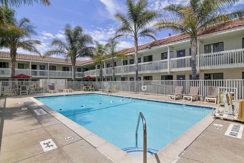 a swimming pool in front of a hotel with palm trees at Motel 6-Lompoc, CA in Lompoc