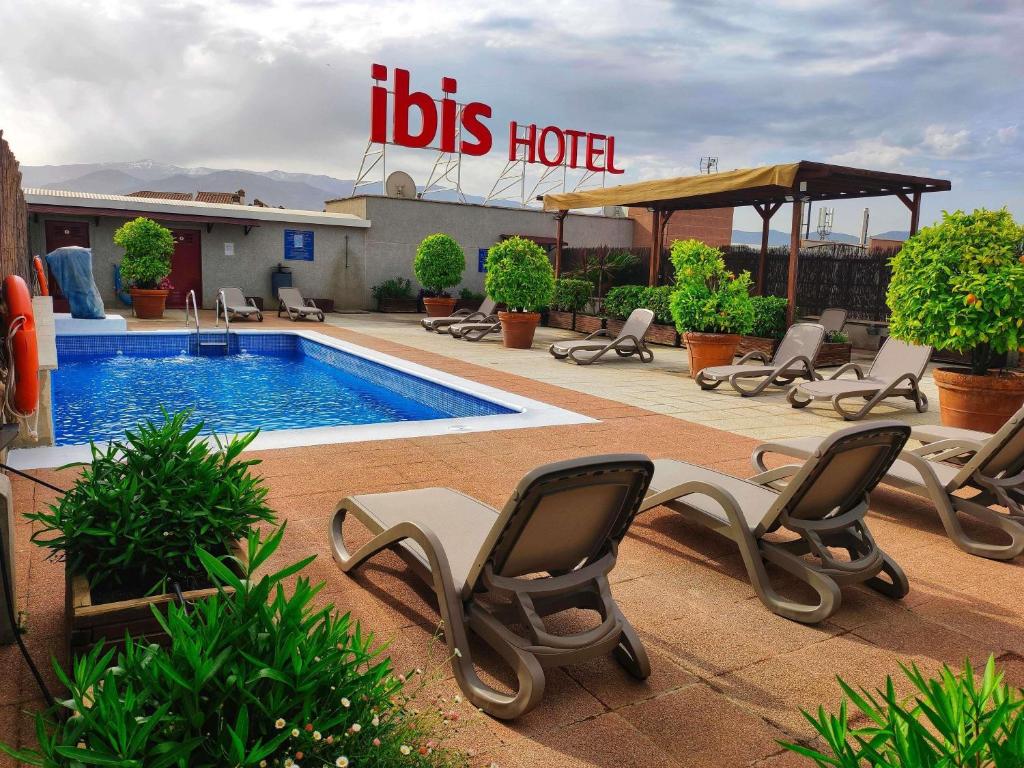 a pool with lounge chairs and a hotel at Ibis Granada in Granada