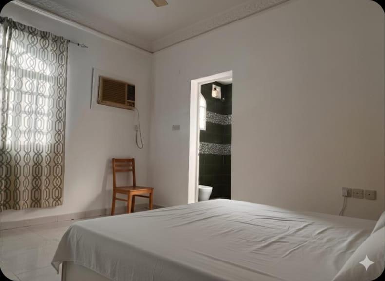 een witte slaapkamer met een bed en een raam bij Amour Hostel in Seeb